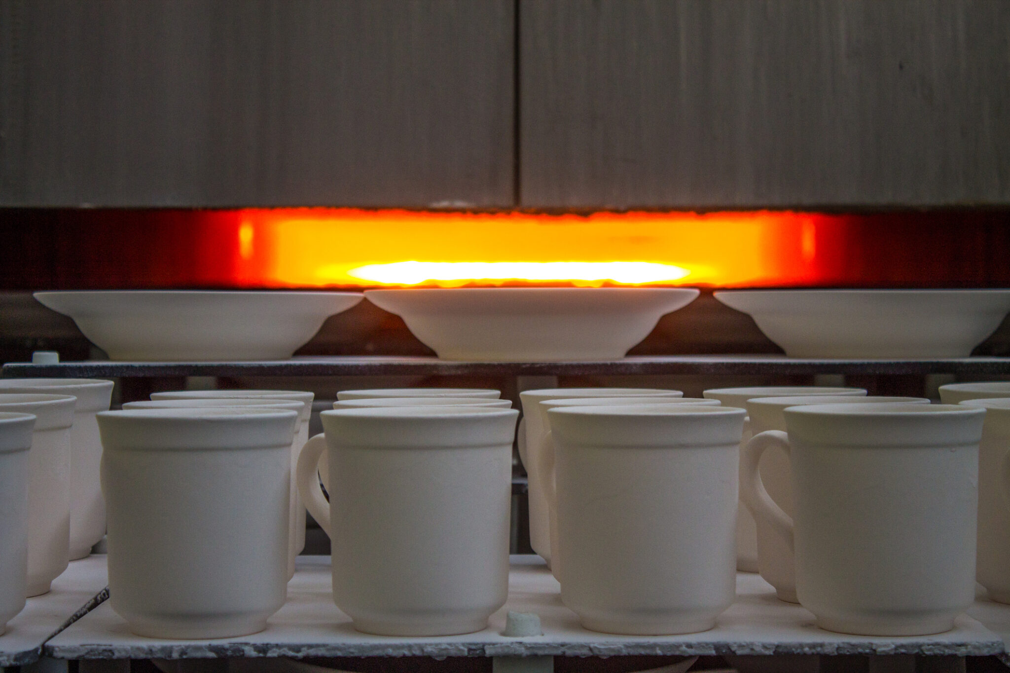 Porcelain white mugs are fired in a muffle furnace in the workshop of a porcelain factory in Likino Dulevo and copy space